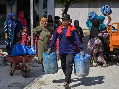 Warga membawa jeriken saat pendiistribusian air  bersih oleh Palang Merah Indonesia (PMI) Kabupaten Bangkalan di Dusun Batangan Tengah, Desa Batangan, Kecamatan Tanah Merah, Kabupaten Bangkalan, Jawa Timur, Selasa (21/7/2026). (AFP/ Juni Kriswanto)