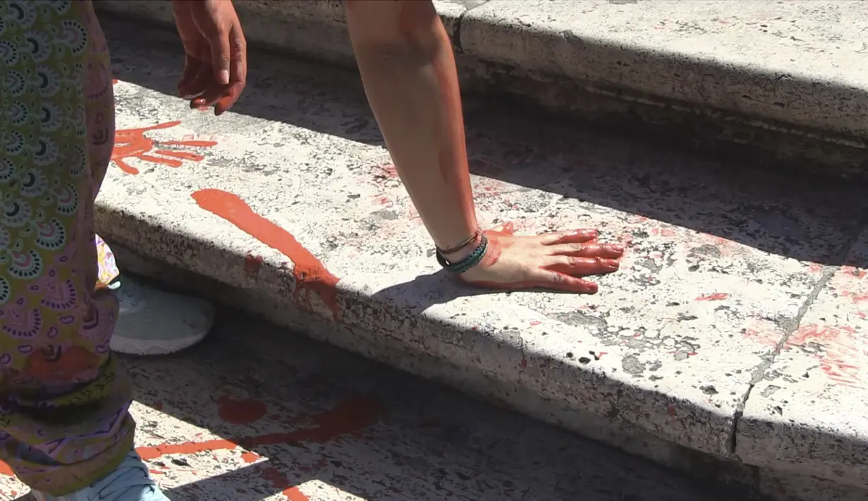 Para anggota gerakan yang disebut "Bruciamo tutto" -  atau "Let's Burn Everything," - menuangkan kaleng-kaleng cairan tersebut ke Spanish Steps dan juga membuat cetakan tangan dengan cairan cat tersebut. (Lapresse via AP)