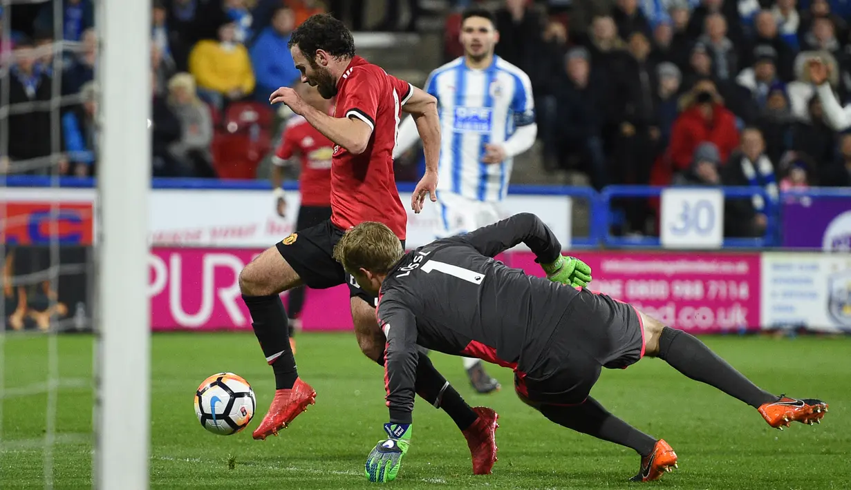 Gelandang Manchester United, Juan Mata berusaha dihadang oleh kiper Huddersfield Town, Jonas Lossl pada pertandingan putaran kelima Piala FA di John Smith's Stadium, Minggu (18/2). MU melaju ke perempatfinal Piala FA setelah menang 2-0. (Oli SCARFF/AFP)
