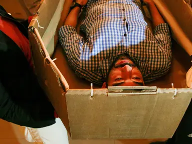  Elio Angulo saat mencoba ukuran peti mati dari karton di kamar mayat di Valencia, negara bagian Carabobo, Venezuela, Kakis (25/08). Krisis peti mati telah menjadi begitu menyedihkan. (REUTERS/Marco Bello).