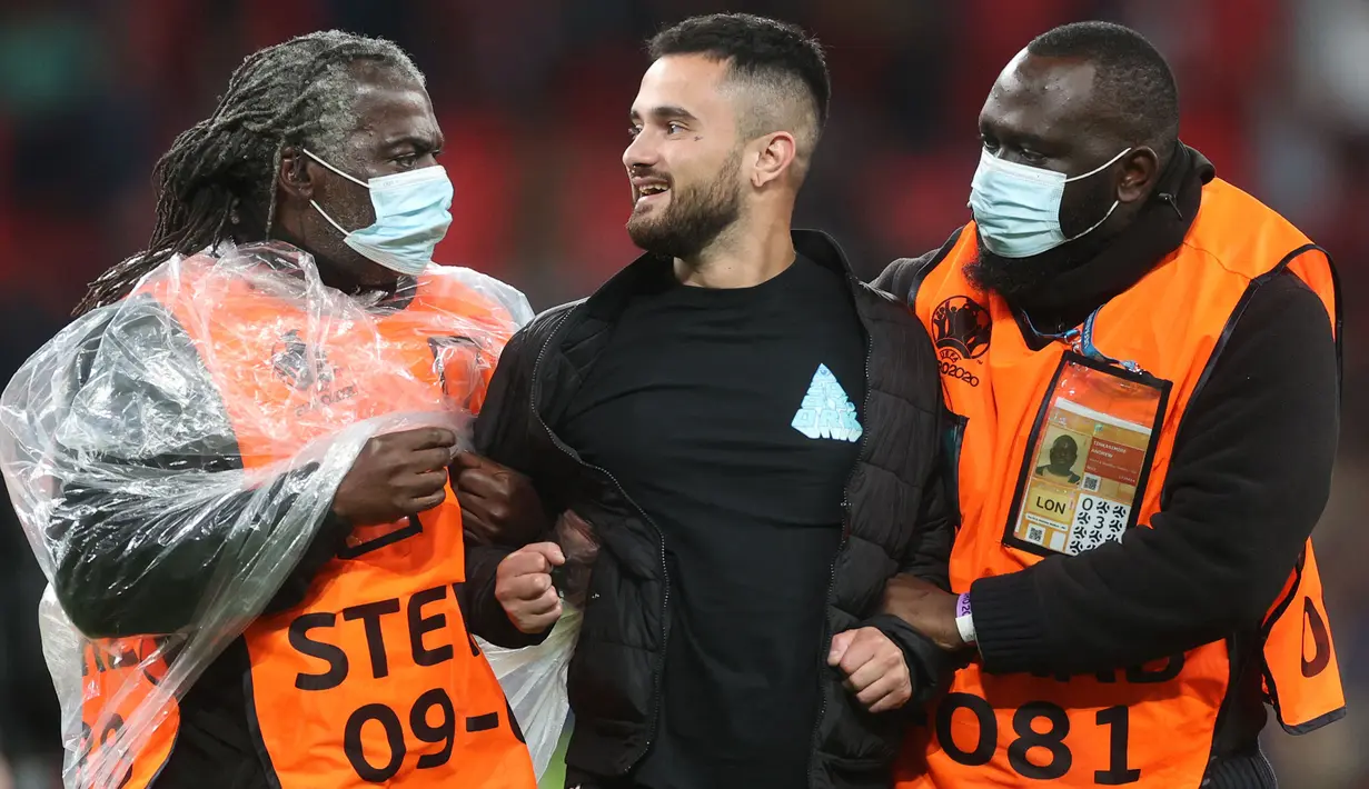 Petugas keamanan menahan seorang penyusup lapangan setelah pertandingan sepak bola Semifinal UEFA EURO 2020 antara Italia melawan Spanyol yang berlangsung di Stadion Wembley, London, Inggris pada 6 Juli 2021. (AFP/Pool/Carl Recine)
