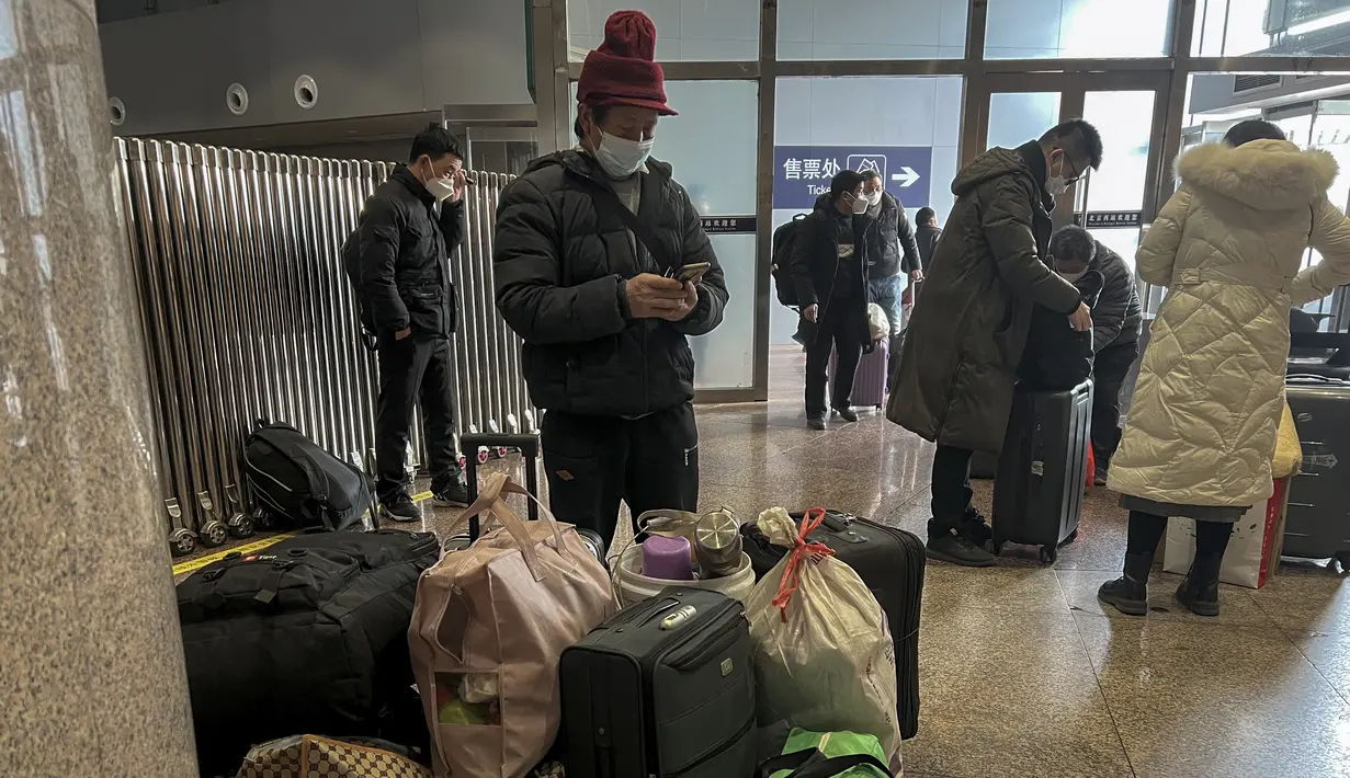 Para pelancong yang mengenakan masker dengan barang bawaan mereka tiba di Stasiun Kereta Api Barat di Beijing, Jumat (6/1/2023). China berupaya meminimalkan kemungkinan wabah COVID-19 yang lebih besar selama kesibukan perjalanan Tahun Baru Imlek bulan ini menyusul berakhirnya sebagian besar langkah-langkah pencegahan pandemi. (AP Photo/Wayne Zhang)