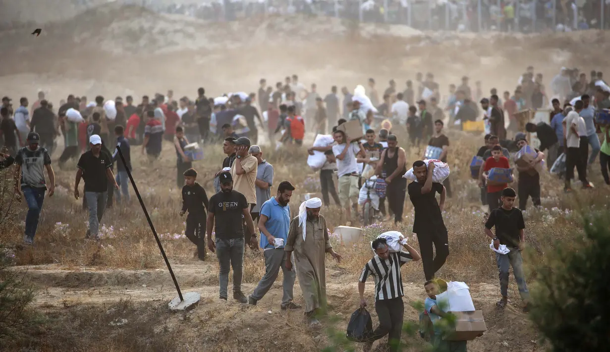 Orang-orang membawa pasokan bantuan dari Gaza Humanitarian Foundation (GHF), sebuah kelompok bantuan swasta yang didukung oleh Amerika Serikat, di Jalur Gaza Tengah pada 8 Juni 2025. (Eyad BABA/AFP)