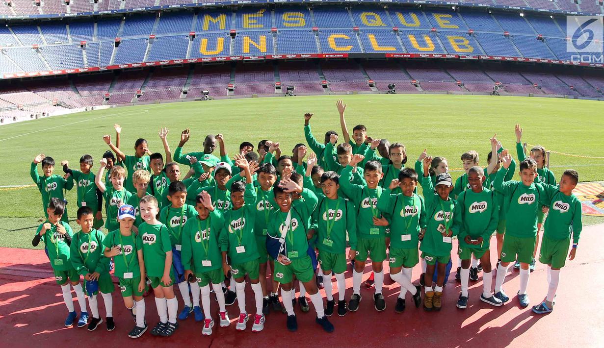 Delapan pemain terbaik MILO Football Championship 2018 yang mendapatkan kesempatan berlatih berpose bersama puluhan anak lainnya dari seluruh dunia di dalam stadion Nou Camp, Barcelona, Spanyol. (Liputan6.com/Rizky)
