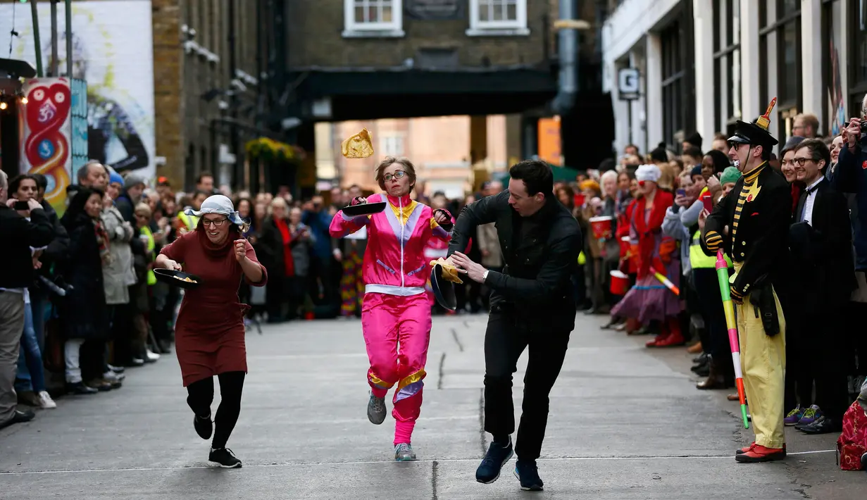 Para peserta berlari membawa wajan berisi pancake dalam acara tahunan Great Spitalfields Pancake Race di London, Inggris, Selasa (9/2). Dalam lomba itu, peserta diwajibkan berlari sambil membalik pancake tanpa membuatnya terjatuh. (REUTERS/Stefan Wermuth)