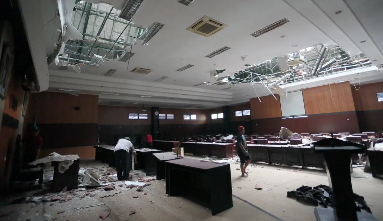 Para pekerja membersihkan puing-puing akibat gempa dari aula gedung DPRD di Blitar, Jawa Timur, Sabtu (10/4/2021). Gempa bermagnitudo 6,0 melanda lepas pantai pulau Jawa Indonesia pada Sabtu 10 April 2021. (Photo by M. ULIN NUHA / AFP)