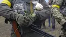 Seorang anggota Pasukan Pertahanan Teritorial Ukraina memegang bunga selama upacara pernikahan untuk Lesia Ivashchenko dan Valerii Fylymonov di pos pemeriksaan di Kiev, 6 Maret 2022. Kedunya menikah dengan upacara seadanya yang dilakukan korps mereka di tengah invasi Rusia. (AP/Efrem Lukatsky)