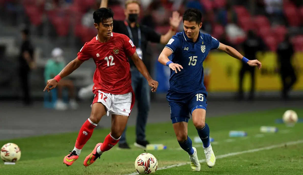 Pemain Indonesia Pratama Arhan Alif Rifai (kiri) berebut bola dengan pemain Thailand Narubadin Weerawatnodom pada pertandingan sepak bola leg kedua final Piala AFF 2020 di National Stadium, Singapura, Sabtu (1/1/2022). Pertandingan berakhir dengan skor 2-2. (Roslan RAHMAN/AFP)