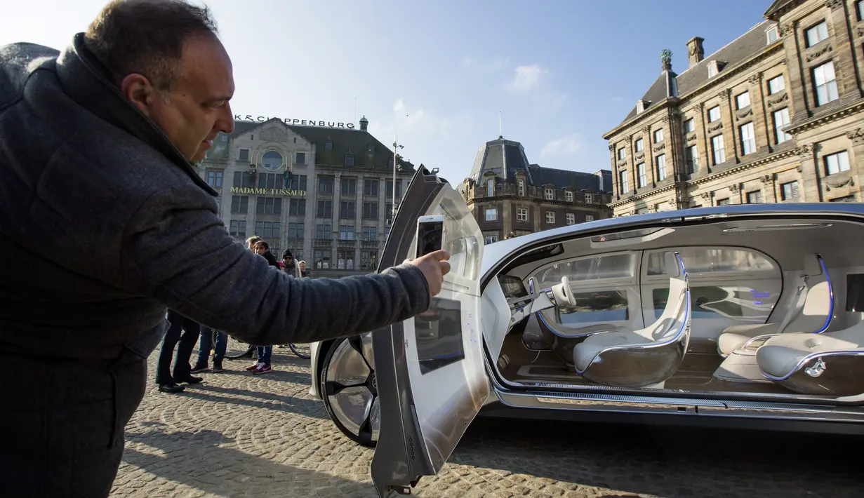Seorang warga mengambil gambar interior  dari Mercedes Benz F 015 saat dipamerkan di Dam Square, Amsterdam, Belanda, Minggu (13/3/2016). Bentuknya yang unik dan futuristik membuat kehadirannya menjadi pusat perhatian warga Amsterdam. (AFP Photo/Bart Maat)