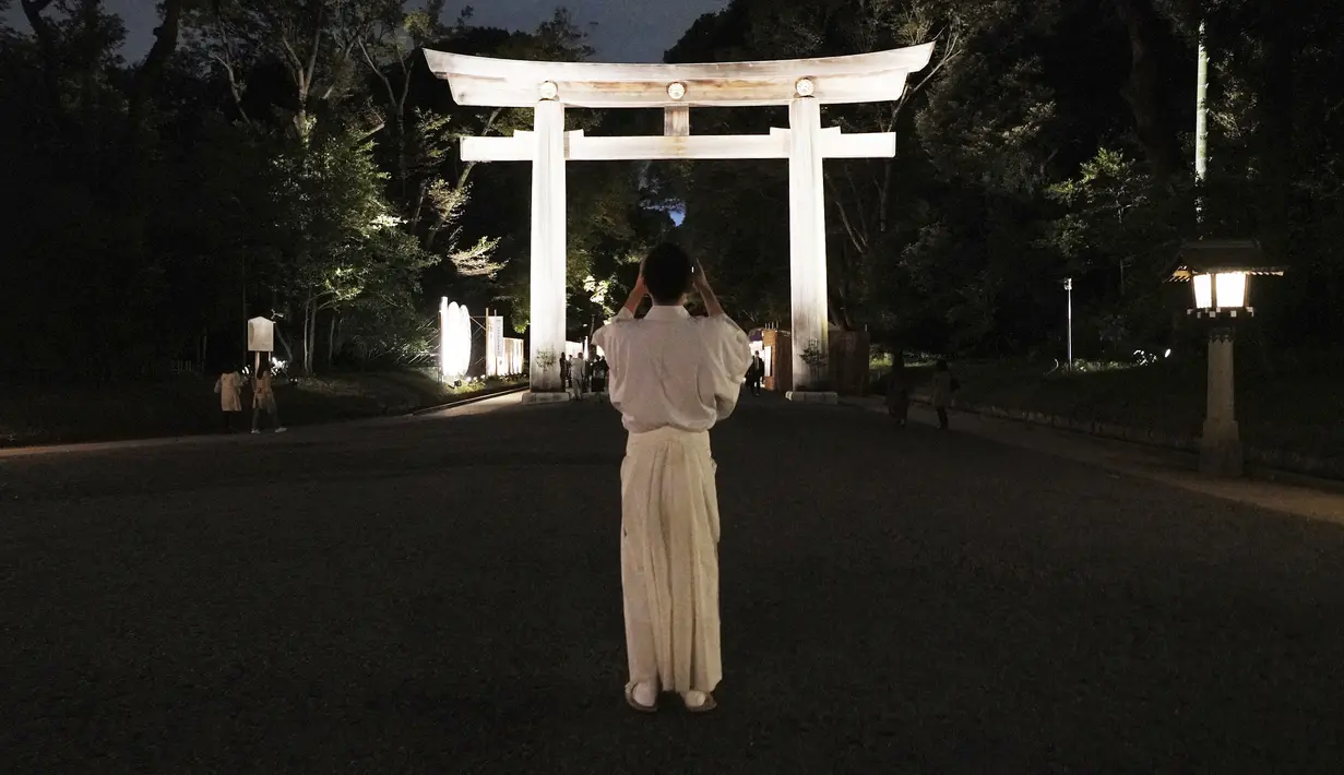 Pendeta kuil mengambil foto sebuah torii, atau gerbang kuil di Kuil Meiji Jingu Shinto untuk menandai peringatan 100 tahun berdirinya di Tokyo, Jumat (30/10/2020). Meiji Jingu, dibangun untuk memberi penghormatan kepada Kaisar Meiji dan Permaisuri Shoken pada tahun 1920 (AP Photo/Eugene Hoshiko)