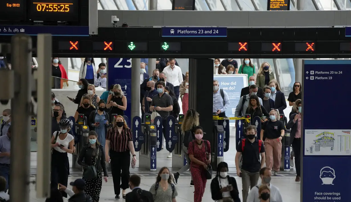 Orang-orang memakai masker setelah turun dari kereta api pada jam sibuk pagi hari di stasiun Waterloo di London, Rabu (13/7/2021). Wali Kota Sadiq Khan menekankan transportasi publik di London akan terus memberlakukan kewajiban memakai masker setelah Senin (19/7) mendatang. (AP Photo/Matt Dunham)