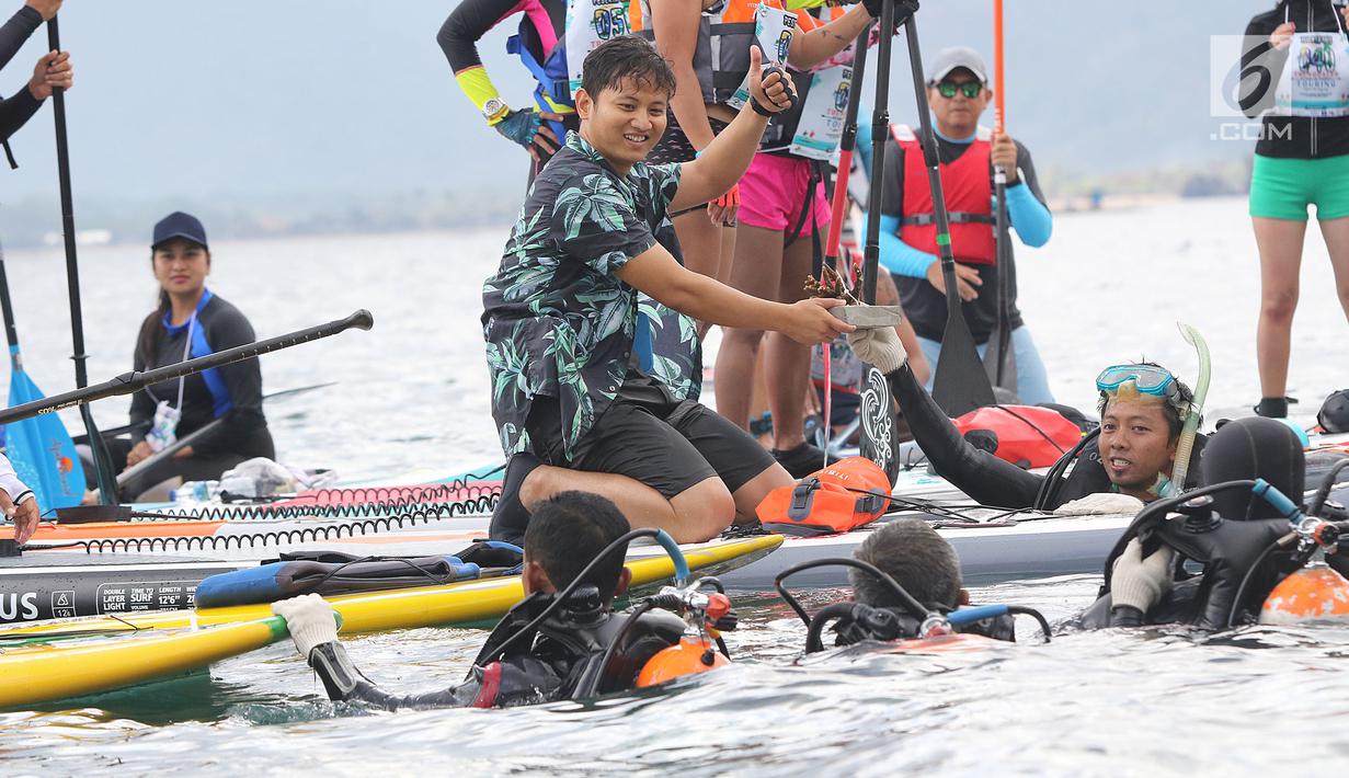 Bupati Trenggalek, Mochammad Nur Arifin menyerahkan secara simbolis terumbu karang ke penyelam di Pantai Mutiara, Trenggalek, Jawa Timur, Sabtu (7/9/2019). BPJS Ketenagakerjaan memberikan bantuan 100 terumbu karang agar ekonomi semakin meningkat. (Liputan6.com/Herman Zakharia)