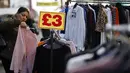 <p>Sebuah tanda menampilkan harga pakaian saat pembeli melihat-lihat barang di kios pasar di Walthamstow Market, London, Minggu (22/11/2021). Inflasi Inggris telah mencapai level tertinggi 10 tahun karena tagihan energi rumah tangga meroket, menurut data minggu lalu. (Tolga Akmen/AFP)</p>