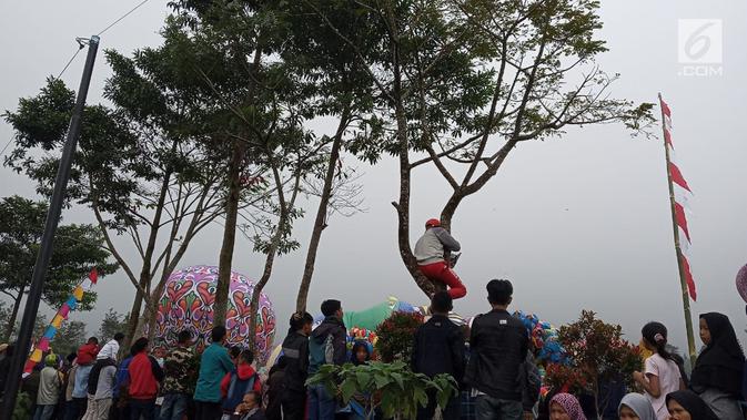 Sejumlah warga melihat balon udara dinaikan di Lapangan Pagerejo, Kertek, Kabupaten Wonosobo,  Sabtu (15/6/2019). Festival ini untuk memeriahkan syawalan dan wujud syukur warga yang hidup di lereng gunung sindoro dan sumbing. (Liputan6.com/Gholib)