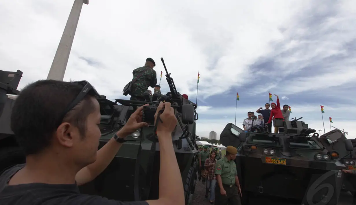 Sejumlah pengunjung berfoto di atas tank saat pameran alutsista TNI AD di kawasan Monas, Jakarta, Jumat (12/12/2014). (Liputan6.com/Faizal Fanani)