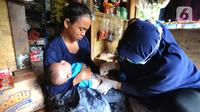 Petugas medis Puskesmas Cisimeut Bidan Pite memberikan imunisasi DPT 1 kepada bayi 3 bulan Posyandu keliling di Kampung Baduy Luar Gazebo, Kanekes, Banten, (Rabu (27/01/2021). Setiap bulannya Bidan Pite berkeliling Baduy Luar sepanjang 14 km pulang pergi berjalan kaki. (merdeka.com/Arie Basuki)