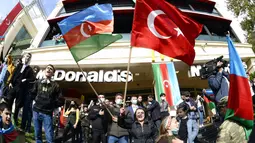 Rakyat Azerbaijan mengibarkan bendera nasional dan Turki di Baku, Azerbaijan, Selasa (10/11/2020). Armenia dan Azerbaijan mengumumkan perjanjian damai untuk menghentikan pertempuran atas wilayah Nagorno-Karabakh di Azerbaijan berdasarkan pakta yang ditandatangani dengan Rusia. (AP Photo)
