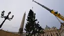 Sebuah derek mengangkat Pohon Natal setinggi 28 meter saat pemasangannya di Lapangan Santo Petrus, Vatikan, Selasa (23/11/2021). Pohon natal raksasa seberat 8 ton yang diambil dari hutan Andalo di wilayah Trentino, itu akan dinyalakan pada 10 Desember mendatang. (Alberto PIZZOLI / AFP)