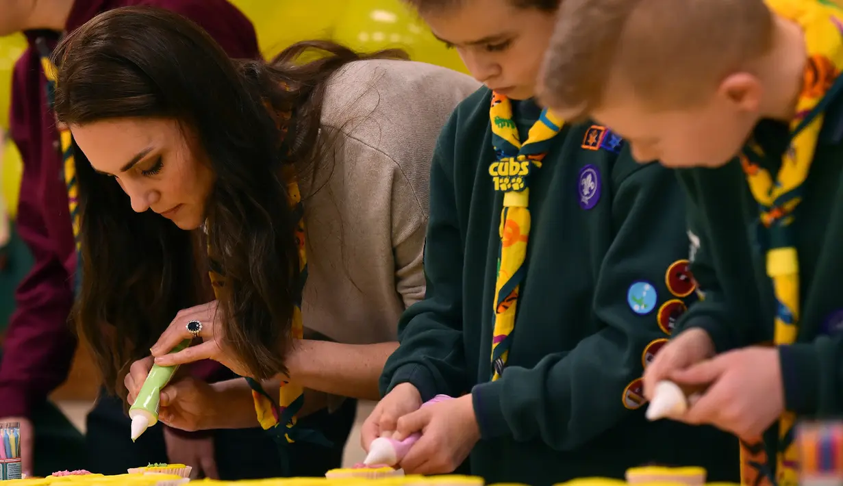 Kate Middleton membuat kue Pramuka bersama sejumlah anak-anak dalam acara Cub Scout Pack di Kings Lynn, Inggris (14/12). Dalam acara ini Kate Middleton bertemu dan bermain dengan 24 anak-anak yang ikut berpartisipasi. (Reuters/Ben Stansall/Pool)