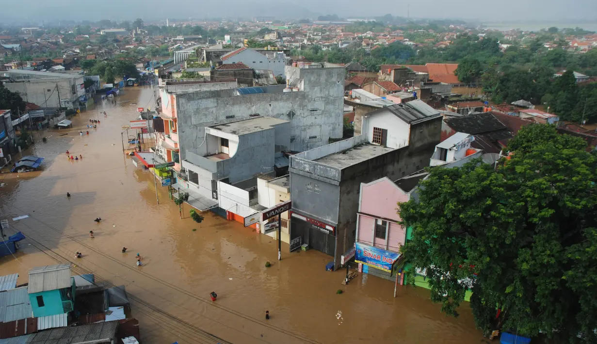 Sejumlah warga melintasi genangan banjir untuk mengungsi di jalan Raya Dayeuhkolot, Kabupaten Bandung, Minggu (13/3). Kawasan Bandung Selatan kembali dilanda banjir akibat luapan Sungai Citarum dan membuat ribuan orang mengungsi. (Timur Matahari/AFP)