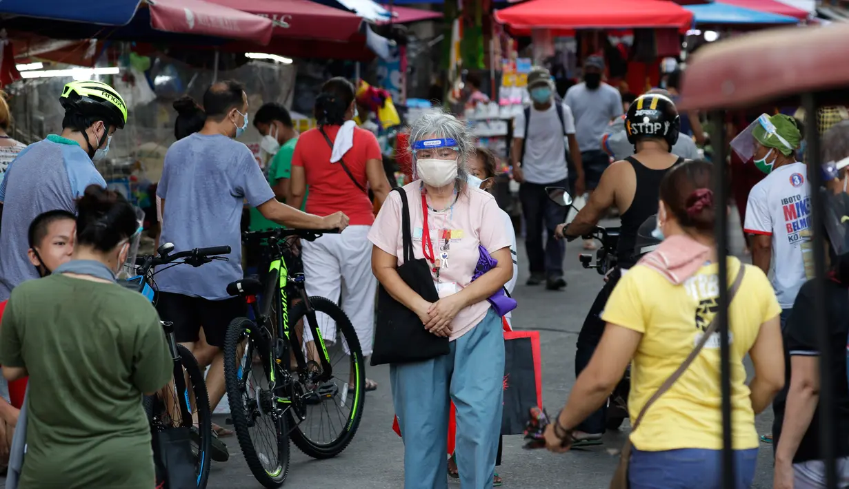 Seorang perempuan yang mengenakan masker berjalan di sepanjang kios darurat, setelah pelonggaran lockdown, di pusat kota Manila, Filipina, Rabu (2/9/2020). Pemerintah melonggarkan lockdown meskipun negara tersebut memiliki infeksi virus corona terbanyak di Asia Tenggara. (AP Photo/Aaron Favila)