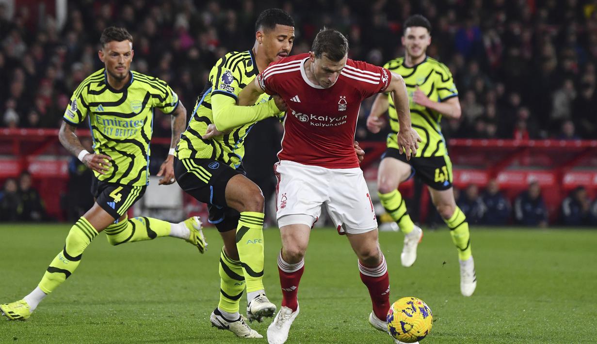 Pemain Arsenal, William Saliba, berebut bola dengan pemain Nottingham Forest, Chris Wood, dalam laga Premier League 2023/2024 pekan 22 di Stadion City Ground, Rabu (31/1/2024). (AP Photo/Rui Vieira)