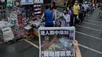 Seorang wanita mencoba mengambil gambar edisi terakhir Apple Daily di depan stan surat kabar di mana orang-orang antre untuk membeli koran di sebuah jalan pusat kota di Hong Kong, Kamis (24/6/2021) Apple Daily mencetak edisi terakhir, Kamis (24/6), setelah 26 tahun beroperasi. (AP Photo/Vincent Yu)