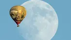 Sebuah balon udara terbang melewati bulan yang terlihat dilangit California, Amerika Serikat 25 September 2015. (REUTERS/Mike Blake)