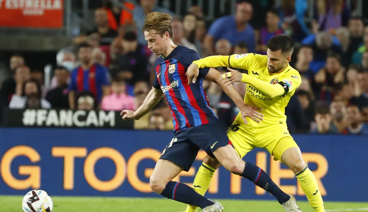 Gelandang Barcelona, Frenkie de Jong mengontrol bola dari kawalan pemain Villareal, Alex Baena pada pertandingan lanjutan La Liga Spanyol di stadion Camp Nou di Barcelona, Spanyol, Jumat (21/10/2022). Berkat kemenangan ini, Barcelona menempati posisi kedua dengan 25 poin dari 10 laga, tertinggal tiga angka dari Madrid yang ada di puncak. (AP Photo/Joan Monfort)