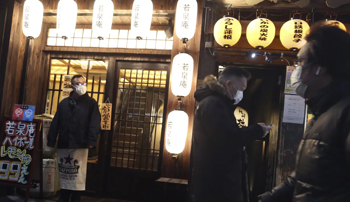 Orang-orang yang mengenakan masker untuk membantu melindungi diri dari penyebaran virus corona berjalan di sepanjang jalan yang dipenuhi bar dan restoran di Tokyo, Selasa (22/3/2022). Langkah-langkah pra-darurat untuk mencegah wabah Covid-19 telah dicabut. (AP Photo/Koji Sasahara)