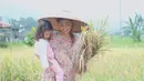 Seperti ibu petani, sambil mengendong putrinya, Thalia dengan mengenakan caping. Menurutnya, ini salah satu caranya untuk mengenalkan padi pada putrinya sebelum akhirnya menjadi beras dan nasi untuk dimakan. (Instagram/ruben_onsu)