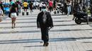 Seorang pejalan kaki berjalan di jalan mengenakan masker di pusat Thessaloniki, Yunani utara (18/5/2022). Mulai 16 Mei, masker wajah tidak lagi diperlukan di banyak penerbangan di Uni Eropa, tetapi Yunani telah mempertahankan aturan maskernya. (AFP/Sakis Mitrolidis)