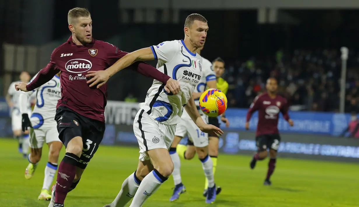 Penyerang Inter Milan Edin Dzeko (kanan) dan bek Salernitana Riccardo Gagliolo bersaing mengincar bola pada giornata ke-18 Liga Italia di Stadion Arechi, Salerno, Sabtu (18/12/2021) dini hari WIB. Inter Milan pesta gol 5-0 di kandang Salernitana. (Carlo Hermann / AFP)