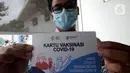 Seorang pria menunjukkan Kartu Vaksinasi COVID-19 saat kegiatan vaksinasi di Puskemas Jagakarsa, Jakarta Selatan, Kamis (14/1/2020). Sejumlah Puskesmas di Jabodetabek mulai melakukan vaksinasi COVID-19 pada hari ini. (merdeka.com/Arie Basuki)