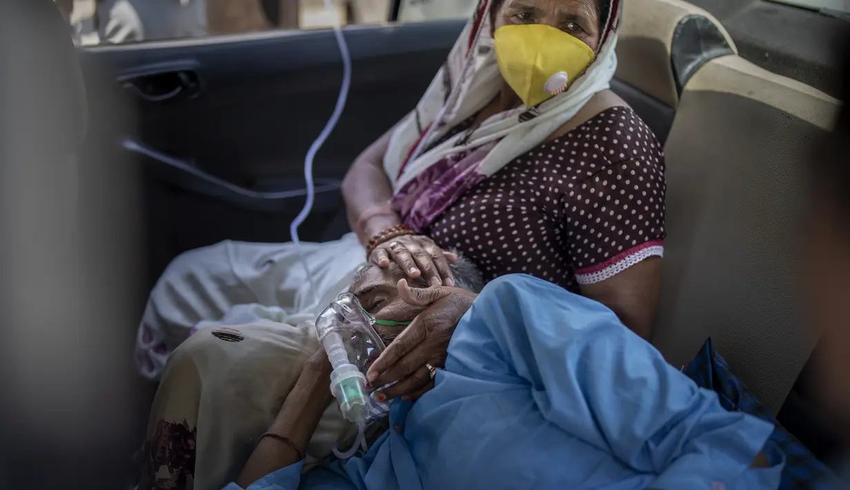 Seorang pasien bernapas dengan bantuan oksigen yang disediakan oleh tempat ibadah Gurdwara, Sikh, di dalam sebuah mobil di New Delhi pada 24 April 2021. India mengalami kekurangan oksigen yang kritis di tengah badai infeksi Covid-19 yang menghancurkan sistem kesehatannya. (AP Photo/Altaf Qadri)