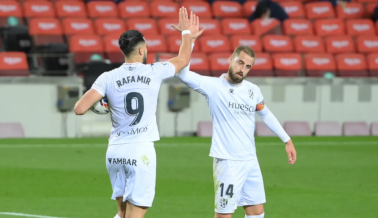 Striker SD Huesca, Rafa Mir (kiri) melakukan selebrasi usai mencetak gol ke gawang Barcelona lewat eksekusi penalti dalam laga lanjutan Liga Spanyol 2020/2021 pekan ke-27 di Camp Nou Stadium, Barcelona, Senin (15/3/2021). SD Huesca kalah 1-4 dari Barcelona. (AFP/Lluis Gene)