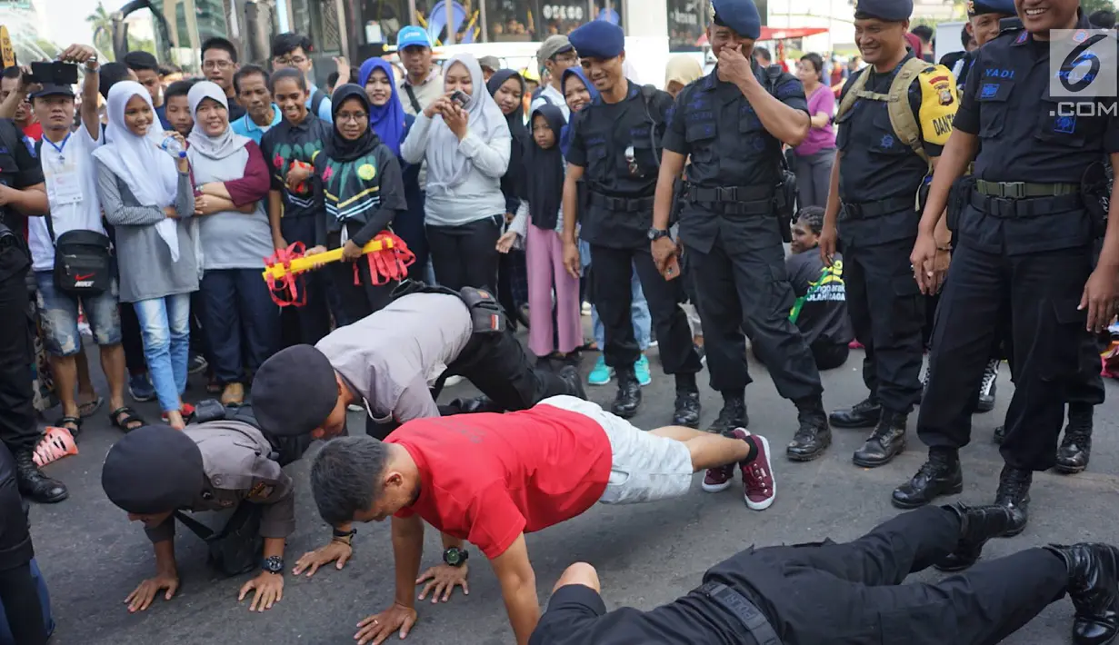 Aparat kepolisian mencoba olahraga push-up bersama komunitas penggerak olahraga di tengah kegiatan Car Free Day kawasan Bundaran Hotel Indonesia, Minggu (30/6/2019). Kegiatan tersebut dalam rangka mengajak masyarakat untuk hidup sehat dengan berolahraga. (Liputan6.com/Immanuel Antonius)
