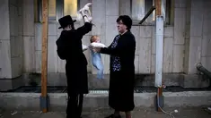 Seorang pria Yahudi Ultra-Ortodoks memegang ayam di atas kepala bayi saat melakukan ritual Kaparot, di Ashdod, Israel, (9/10). Dalam ritual ini ayam putih disembelih sebagai syarat simbolis dari penebusan. (REUTERS/Amir Cohen)