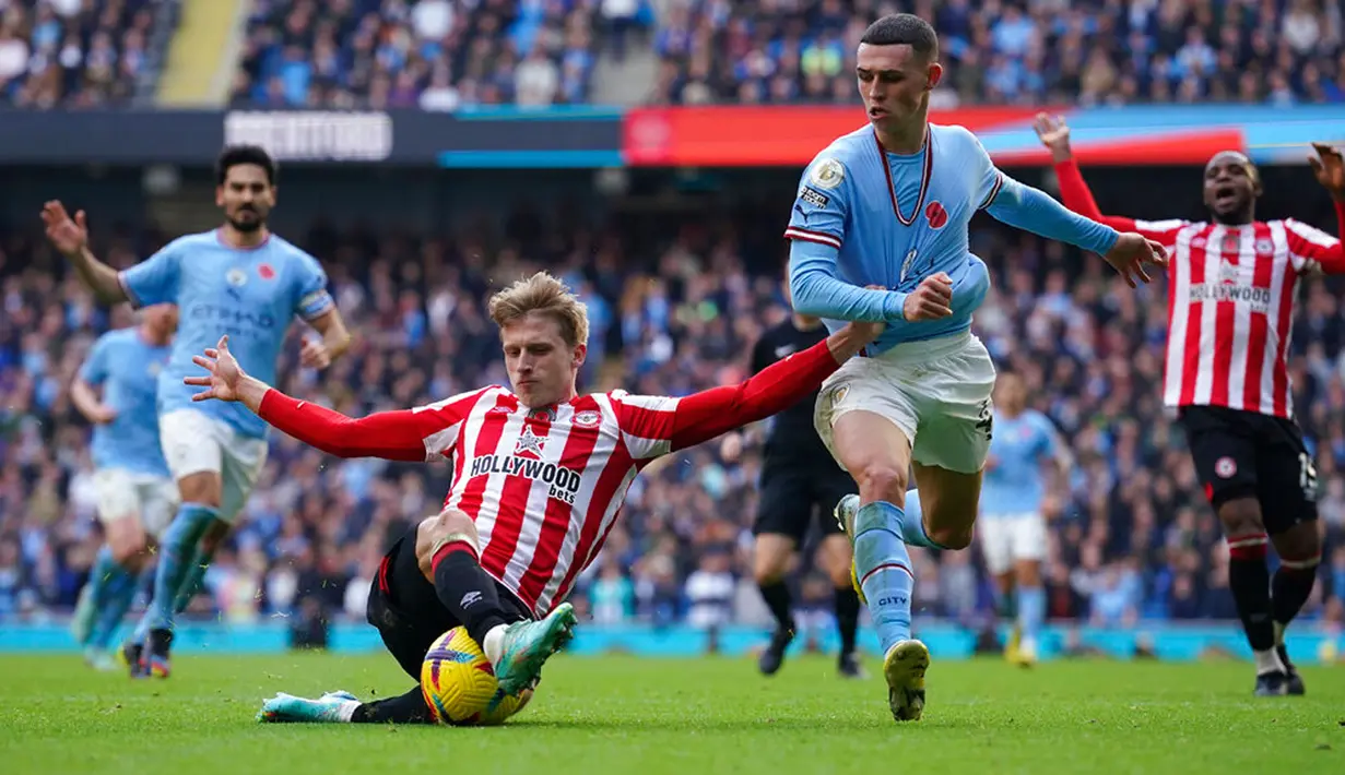 Pemain Brentford Mads Roerslev (kiri) berebut bola dengan pemain Manchester City Phil Foden pada pertandingan sepak bola Liga Inggris di Etihad Stadium, Manchester, Inggris, 12 November 2022. Manchester City kalah 1-2 dari Brentford. (AP Photo/Dave Thompson)