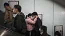 Sepasang suami istri yang mengenakan masker untuk membantu mengekang penyebaran virus corona berpelukan saat mereka keluar dari stasiun kereta bawah tanah pada jam sibuk pagi hari di Beijing, Kamis (29/10/2020). (AP Photo / Andy Wong)