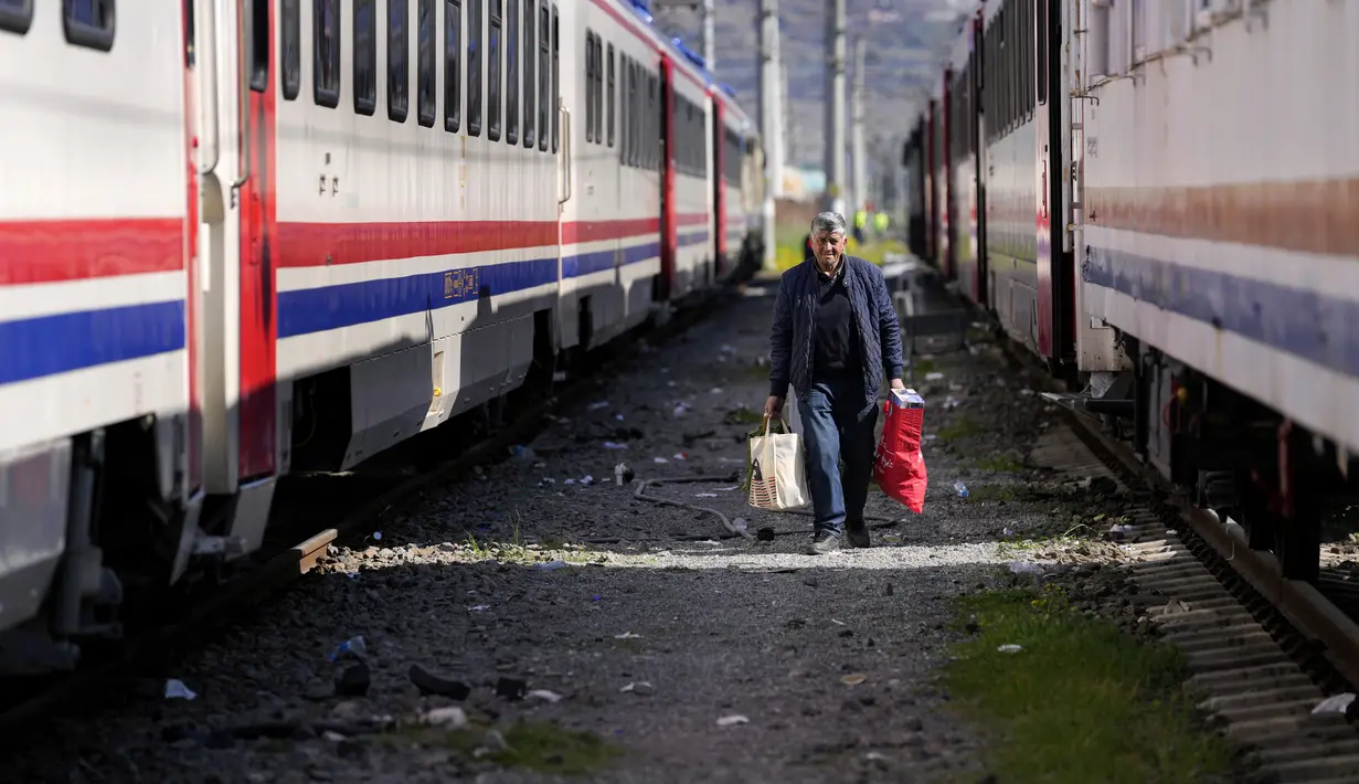 Seorang pria berjalan di antara kereta menggunakan tempat berlindung, di kota Iskenderun, Turki selatan, Selasa (14/2/2023). Ribuan orang kehilangan tempat tinggal akibat gempa dahsyat yang melanda Turki dan Suriah sepekan lalu memadati tenda-tenda yang penuh sesak atau mengantre di jalan-jalan untuk menikmati makanan hangat saat pencarian korban selamat yang putus asa memasuki jam-jam terakhir. (AP Photo/Hussein Malla)