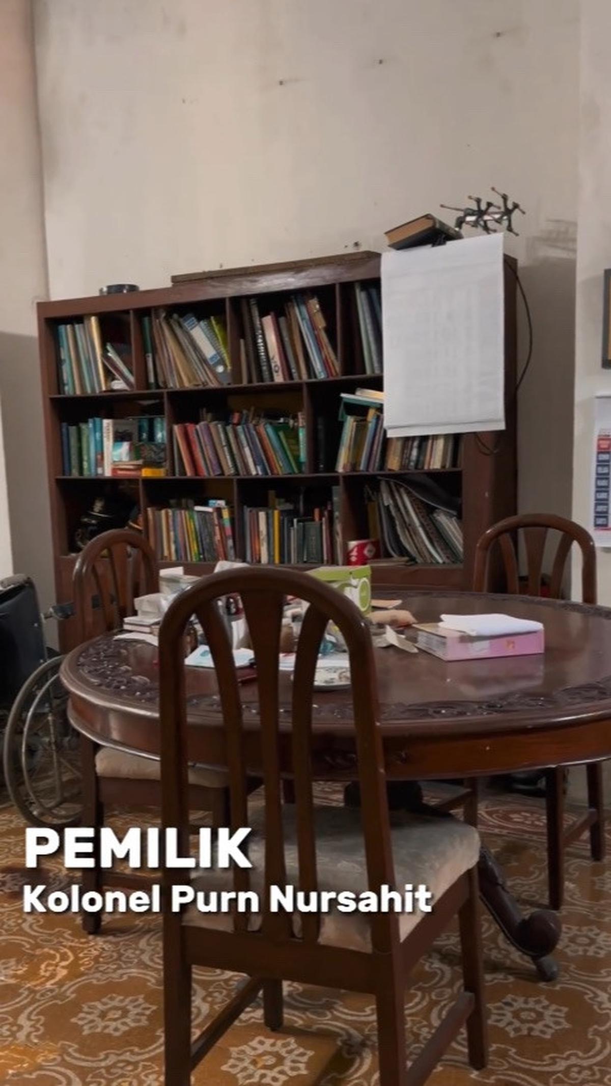 Di sudut lain terdapat sebuah rak buku dari kayu dan satu set meja baca berbentuk bulat. Jika dilihat dari bentuknya, perabot rumah ini masih mempertahankan kekhasan tahun 80-an.