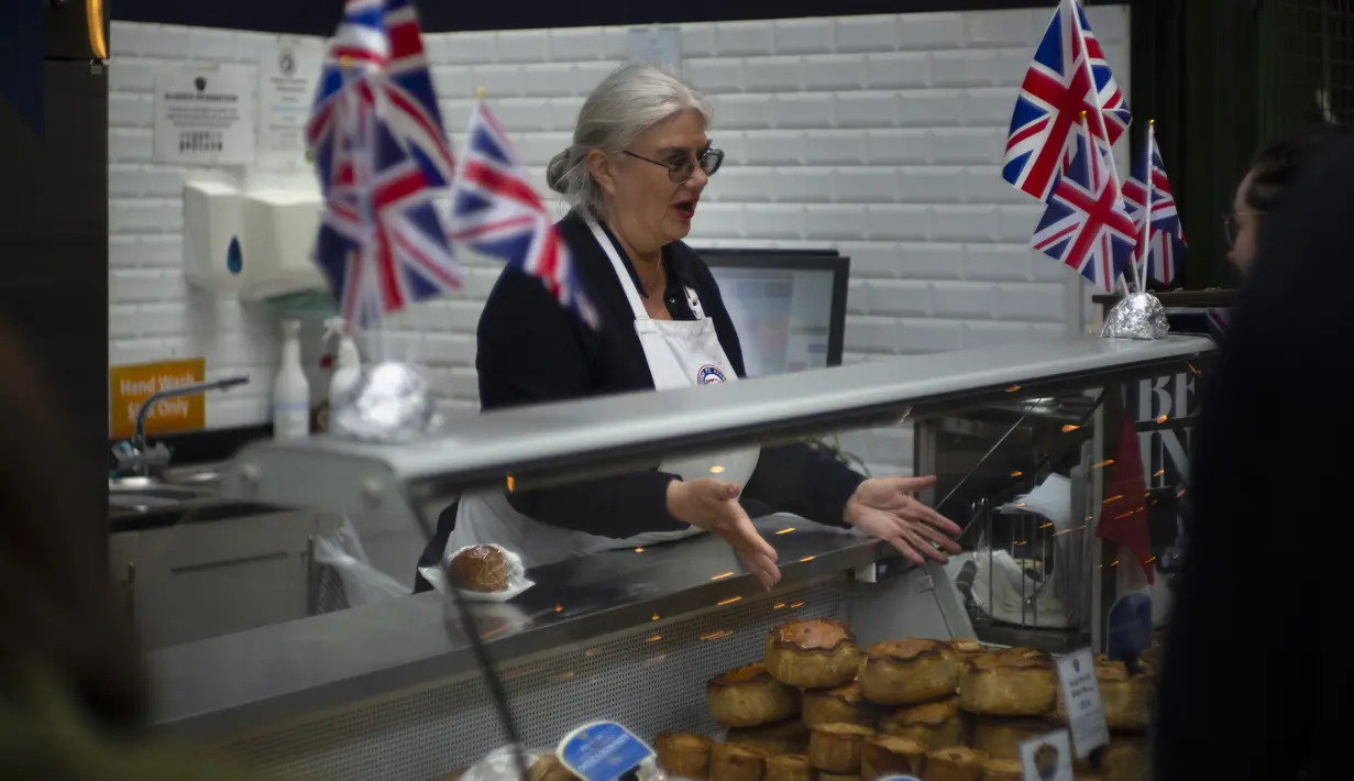 Seorang perempuan menjual pai di pasar di pusat kota London, Jumat, 5 Mei 2023. Penobatan Raja Charles III akan berlangsung di Westminster Abbey pada 6 Mei. (AP Photo/Peter Dejong)