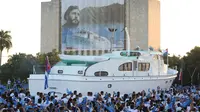 Sebuah replika dari kapal pesiar Granma melintasi spanduk almarhum Presiden Kuba, Fidel Castro yang dipajang selama peringatan Hari Angkatan Bersenjata di Havana, Kuba, Senin (2/1). (Reuters/Desmond Boylan /Pool)
