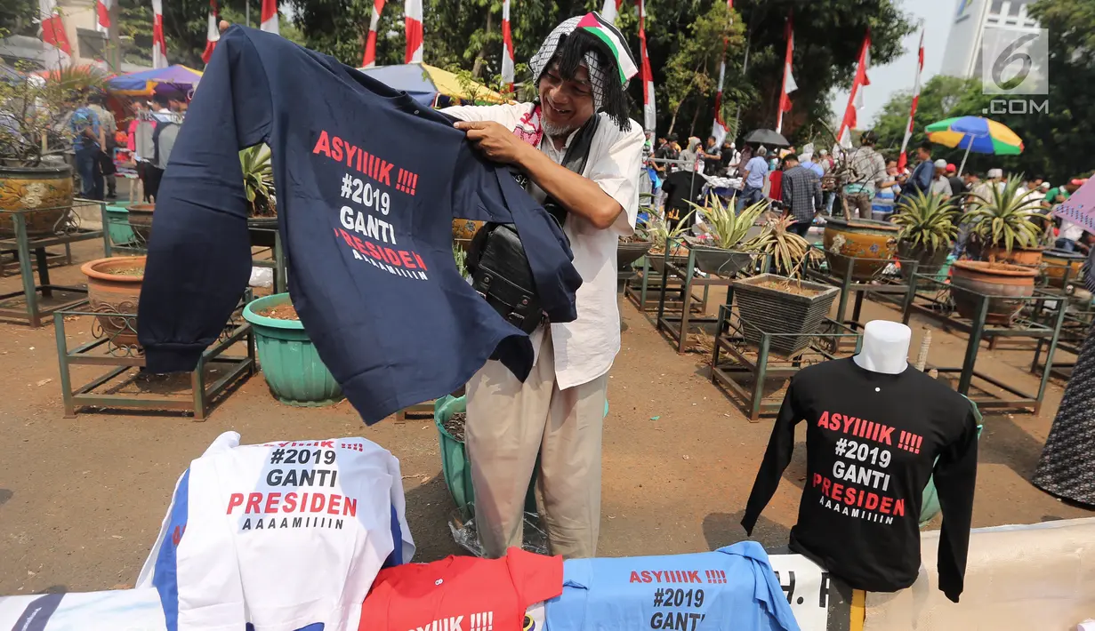 Pedagang menjual kaos #2019GantiPresiden di halaman Masjid Istiqlal, Jakarta, Jumat (10/8). Kaos dijual dengan harga Rp 50-55 ribu per buah untuk lenga pendek dan lengan panjang. (Liputan6.com/Fery Pradolo)