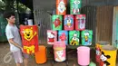Seorang pengrajin lukis tong sampah membawa hasil karyanya yang siap dijual di kawasan serpong, Tangerang Selatan, Senin (20/3). Tong sampah bermotif karakter kartun tersebut di jual seharga 80-125 ribu. (Liputan6.com/Helmi Afandi)
