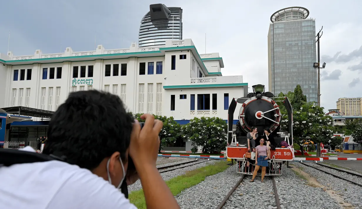 Foto yang diambil pada 5 Juni 2021 menunjukkan sejumlah perempuan berfoto di depan kereta di stasiun kereta api di Phnom Penh. Gerbong kereta diubah menjadi kafe setelah selama pandemi corona sebagian besar perjalanan kereta api di Kamboja dihentikan. (TANG CHHIN Sothy/AFP)