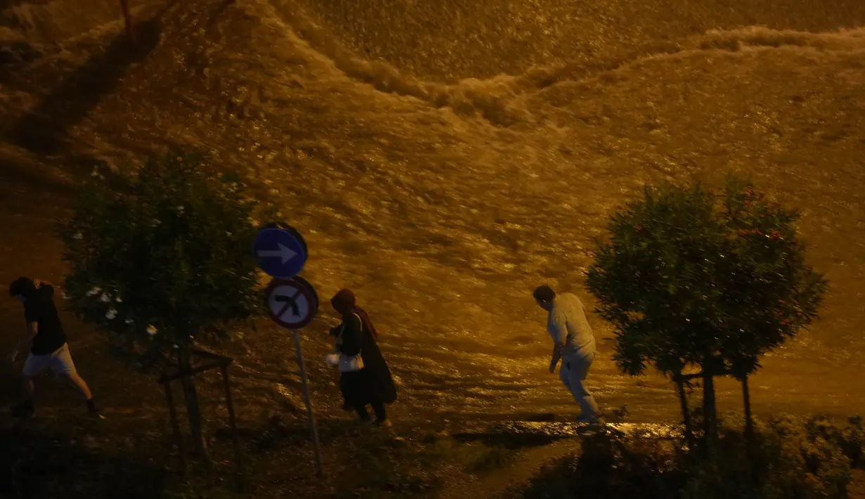 Orang-orang berjalan di samping genangan air akibat hujan deras di distrik Basaksehir, Istanbul, Turki, Selasa, 5 September 2023. (AP Photo/Khalil Hamra)