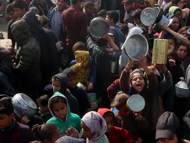 Warga, termasuk anak-anak pengungsi Palestina berkumpul untuk menerima bantuan makanan yang didistribusikan di Deir al-Balah, Jalur Gaza tengah pada 16 Januari 2025. (Eyad BABA/AFP)