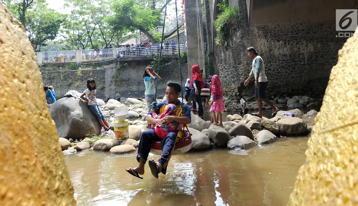 Warga bermain ayunan di kolong jembatan Sempur, Bogor (16/9). Musim kemarau yang menyebabkan debit Sungai Ciliwung menyusut drastis dimanfaatkan warga Bogor dan sekitarnya untuk berwisata murah dan gratis di aliran sungai. (Merdeka.com/Arie Basuki)